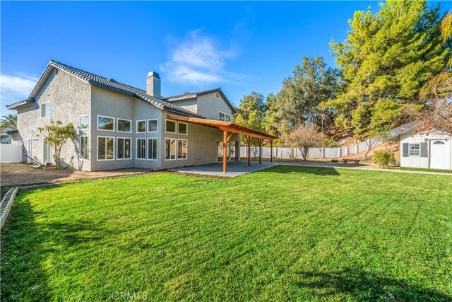 back of house with a chimney, a patio, and stucco siding