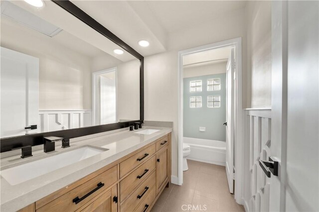 bathroom with toilet, double vanity, recessed lighting, a bathtub, and tile patterned flooring
