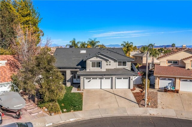 traditional-style house featuring a tiled roof, driveway, an attached garage, stucco siding, and a residential view