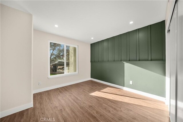 spare room with wood finished floors, baseboards, and recessed lighting