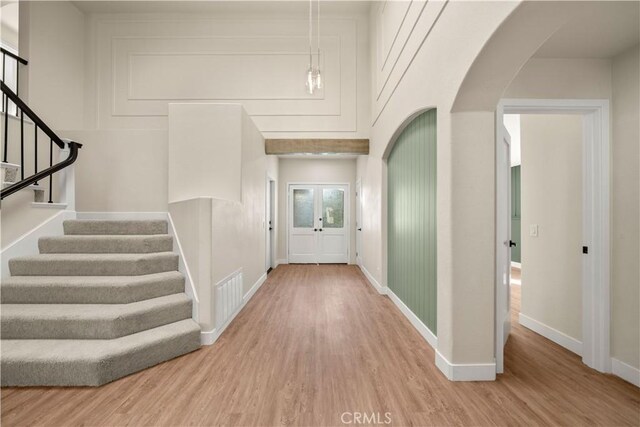 entrance foyer with arched walkways, wood finished floors, stairs, and baseboards