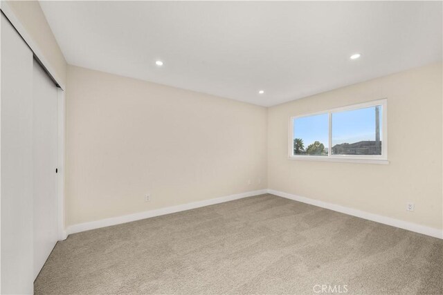 unfurnished bedroom featuring carpet floors, recessed lighting, baseboards, and a closet