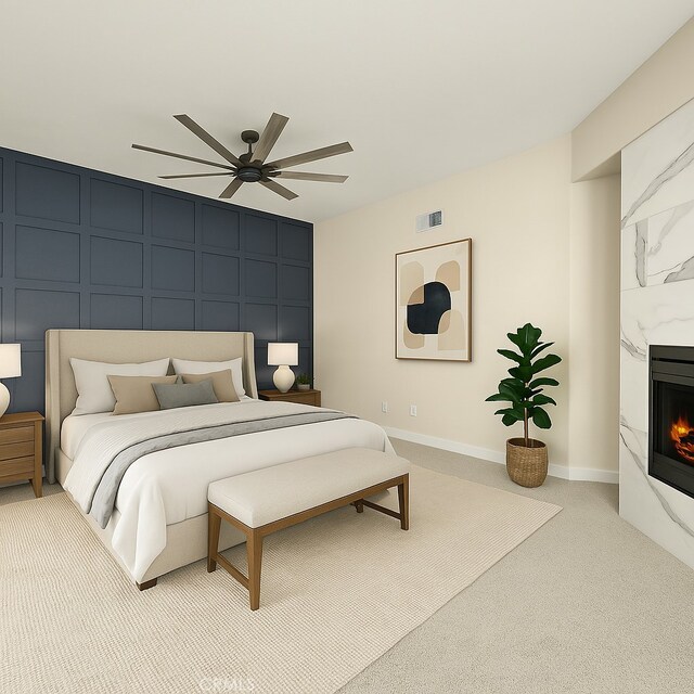 bedroom featuring a decorative wall, a premium fireplace, carpet, and ceiling fan
