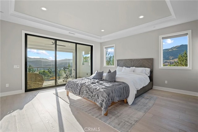 bedroom featuring a raised ceiling, access to exterior, and a mountain view