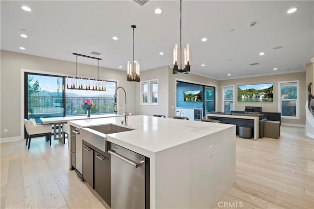 kitchen featuring light hardwood / wood-style floors, a kitchen island with sink, dishwasher, hanging light fixtures, and sink