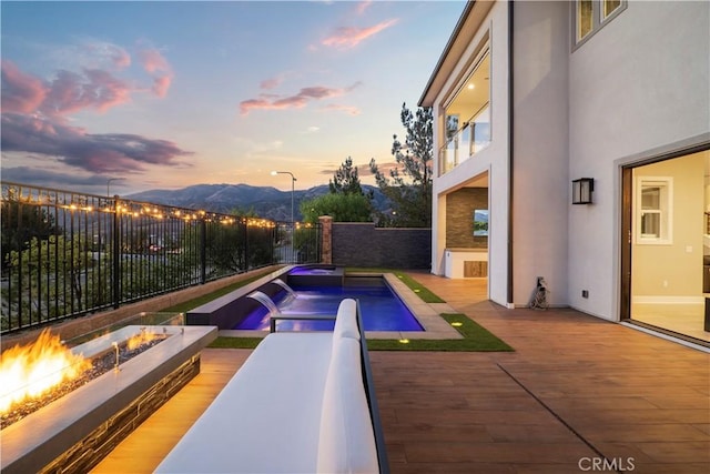 pool at dusk featuring a mountain view and an outdoor fire pit