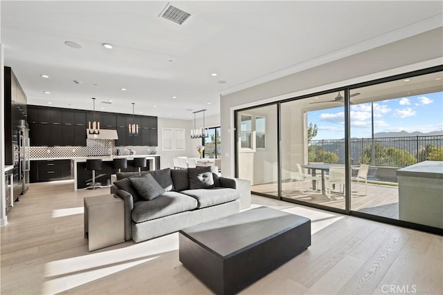 living room featuring a healthy amount of sunlight, crown molding, and light hardwood / wood-style floors