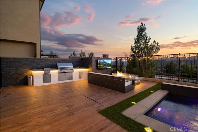 patio terrace at dusk featuring an outdoor fire pit, grilling area, and area for grilling