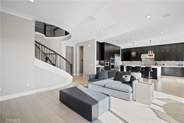 living room with light wood-type flooring and crown molding