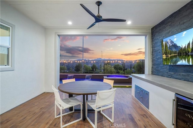 dining space featuring ceiling fan, beverage cooler, and wood-type flooring