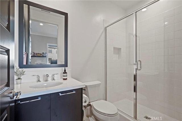 bathroom with toilet, vanity, a shower with shower door, and ornamental molding