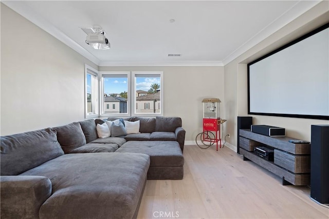 cinema room with ornamental molding and light hardwood / wood-style floors