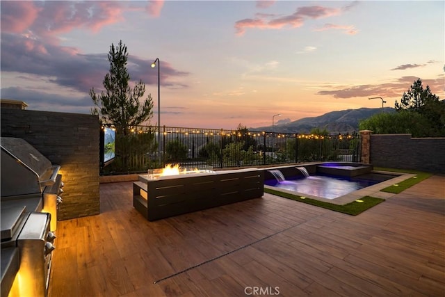 exterior space featuring a mountain view, an outdoor fire pit, a patio area, pool water feature, and area for grilling