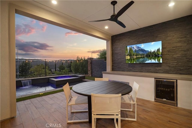 view of patio featuring ceiling fan, beverage cooler, an in ground hot tub, and pool water feature