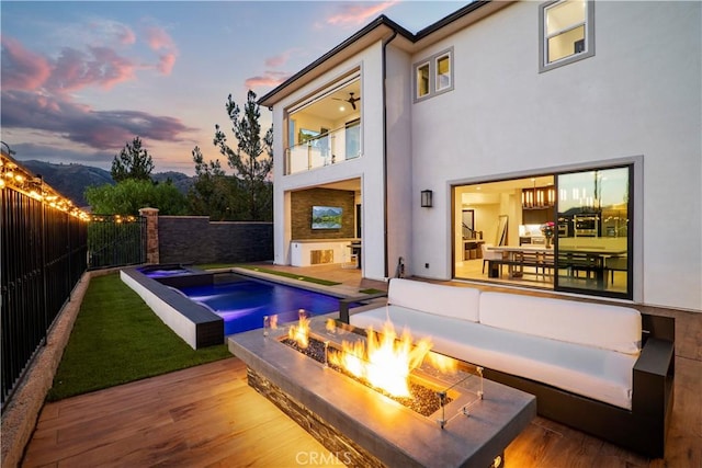 pool at dusk with a deck and an outdoor fire pit