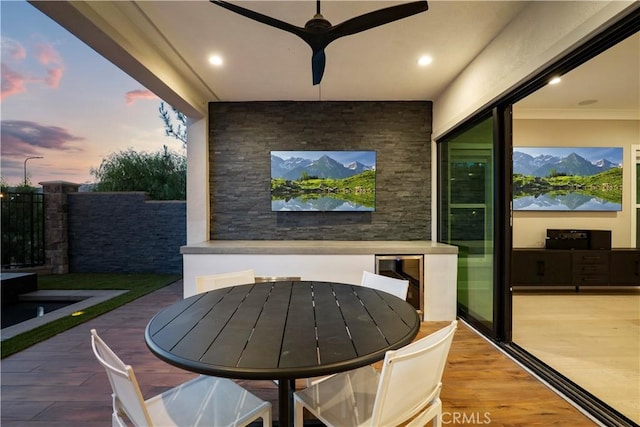 patio terrace at dusk featuring ceiling fan and wine cooler