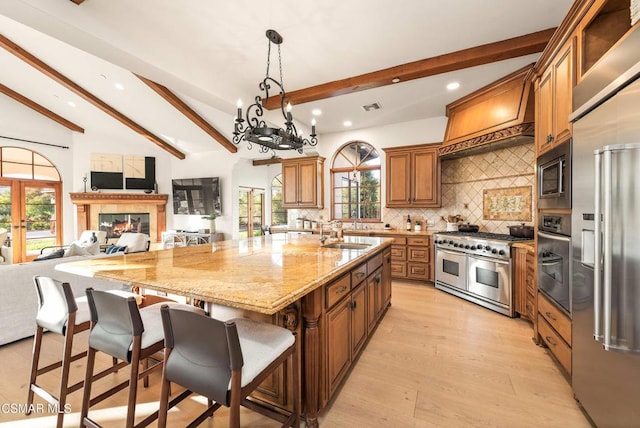 kitchen with backsplash, a kitchen bar, sink, built in appliances, and a large island