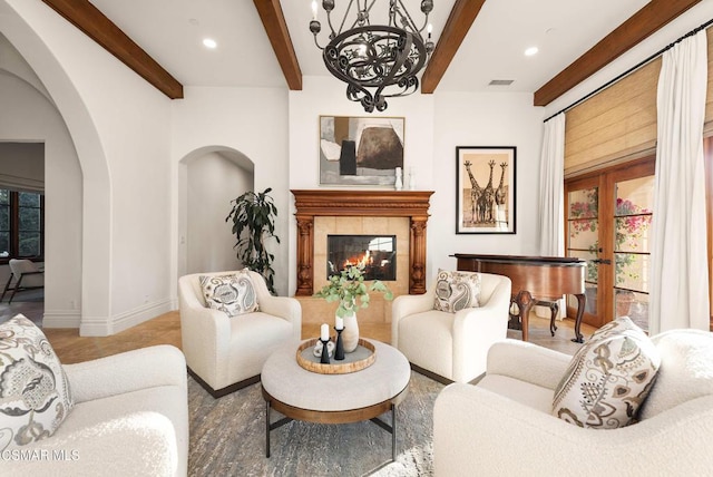 living room featuring a tiled fireplace, a chandelier, french doors, and beamed ceiling