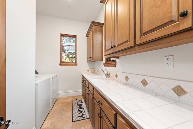 washroom featuring cabinets, light tile patterned flooring, washer and clothes dryer, and sink