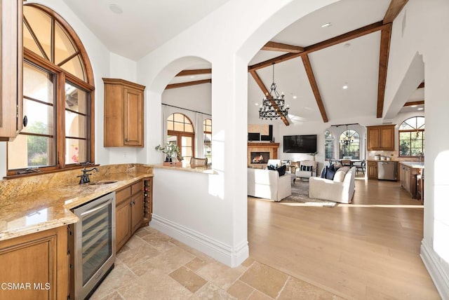 kitchen featuring dishwasher, wine cooler, sink, lofted ceiling with beams, and light stone counters