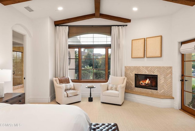 bedroom with carpet floors, a fireplace, vaulted ceiling with beams, and ensuite bath