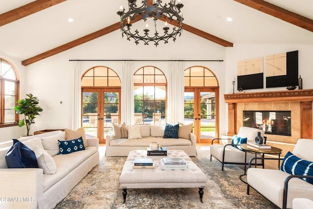 living room featuring a tile fireplace, beamed ceiling, high vaulted ceiling, french doors, and a chandelier