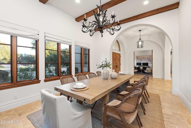 dining room with an inviting chandelier, beam ceiling, and a high ceiling