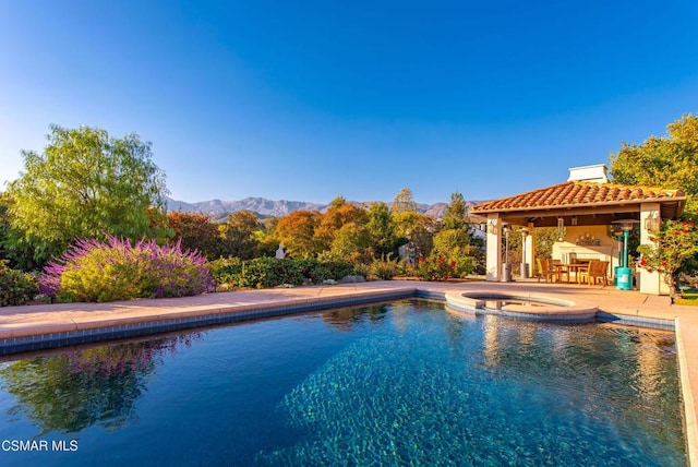 view of swimming pool featuring a patio area, a mountain view, and an in ground hot tub