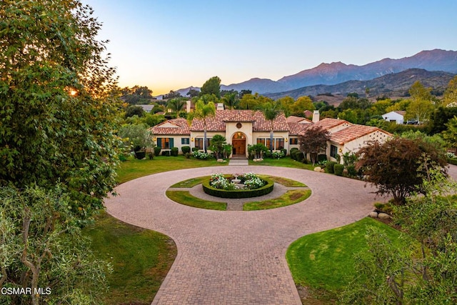 view of front of property with a mountain view and a lawn