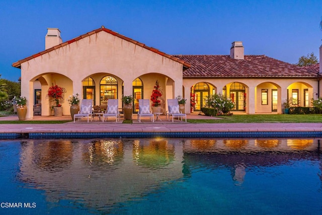 pool at dusk featuring a patio