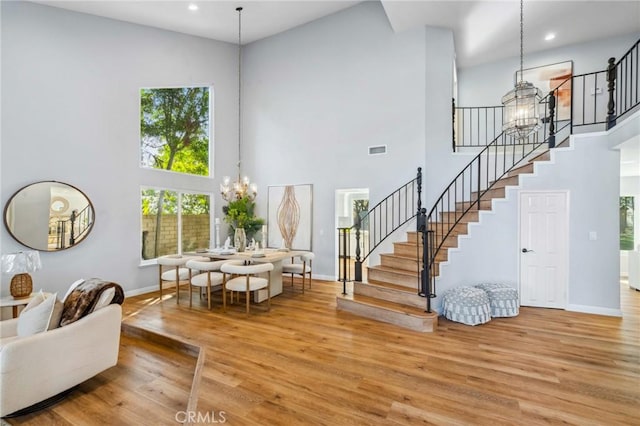 interior space featuring an inviting chandelier, a towering ceiling, and light hardwood / wood-style flooring