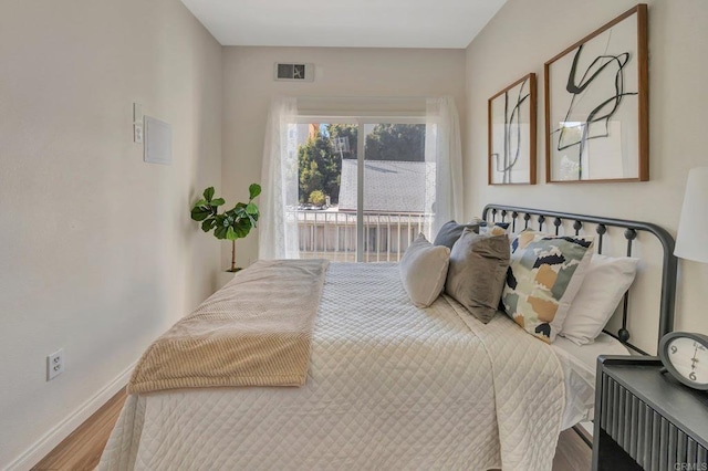 bedroom with access to outside and hardwood / wood-style flooring