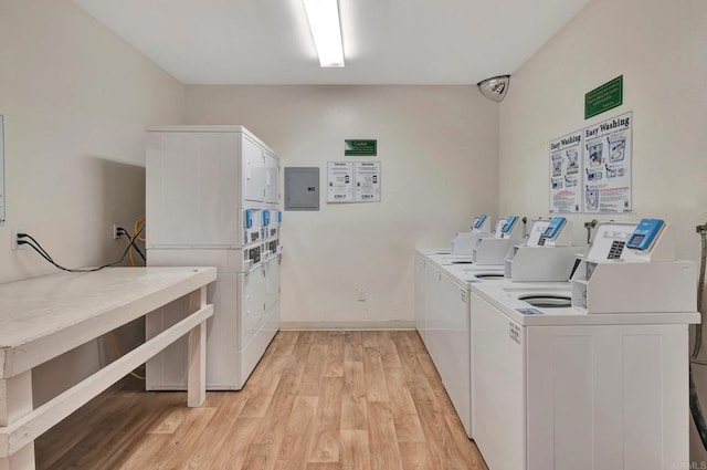 laundry room featuring electric panel, washing machine and dryer, light hardwood / wood-style floors, and stacked washer / dryer