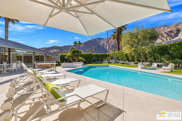 view of pool featuring a patio area, a mountain view, and a hot tub