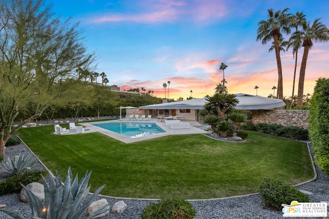 pool at dusk with a patio area and a yard