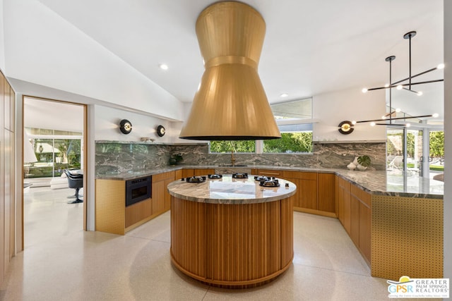 kitchen featuring vaulted ceiling, tasteful backsplash, black oven, and a center island