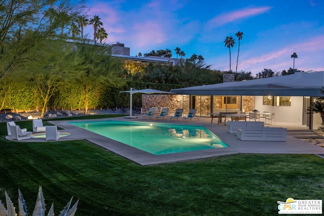 pool at dusk with a patio area and a yard