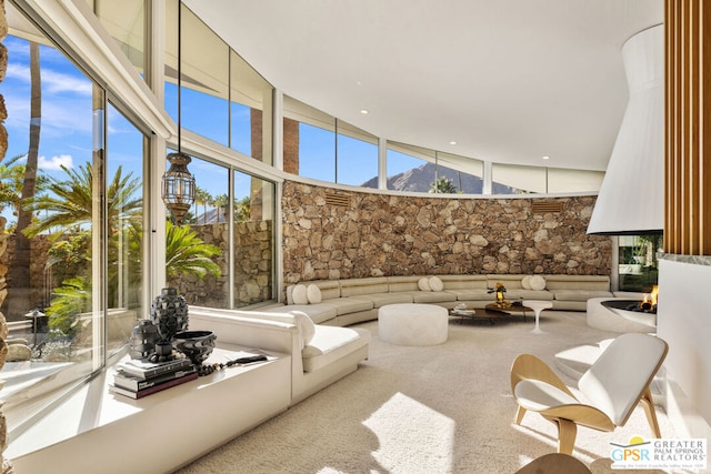 living room with a multi sided fireplace, a high ceiling, and carpet