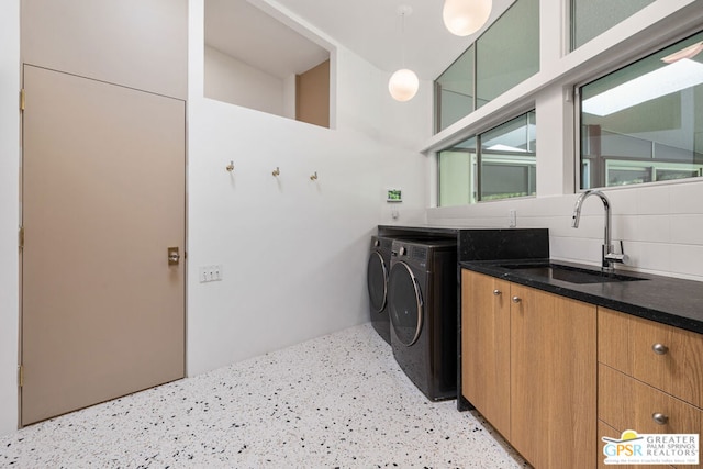 clothes washing area with cabinets, sink, and separate washer and dryer