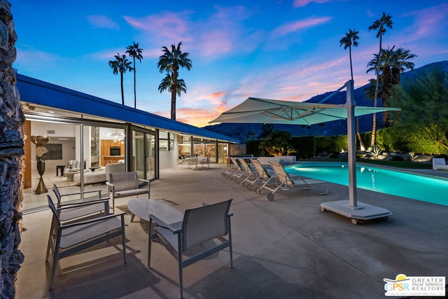 pool at dusk with a patio area