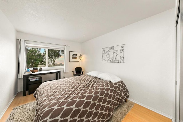 bedroom with light hardwood / wood-style floors and a textured ceiling