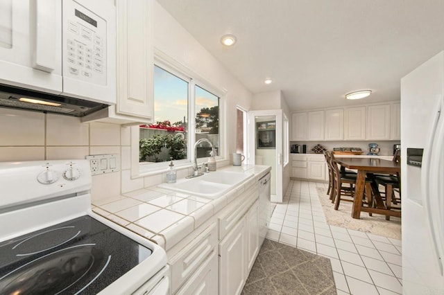 kitchen featuring tile countertops, white appliances, and white cabinetry