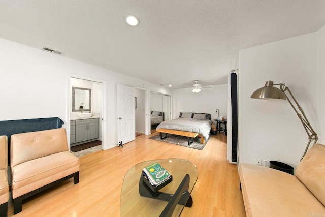 bedroom featuring ceiling fan, sink, connected bathroom, and light wood-type flooring