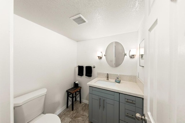 bathroom featuring toilet, vanity, and a textured ceiling