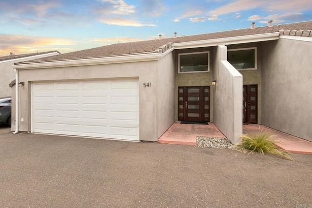 exterior entry at dusk featuring french doors and a garage