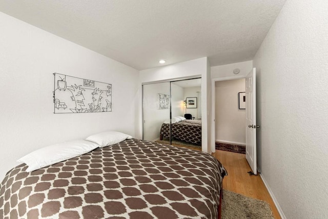 bedroom with a textured ceiling, a closet, and hardwood / wood-style flooring