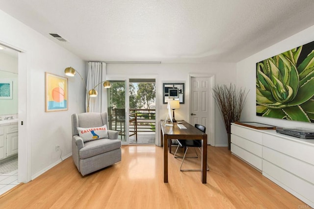 sitting room featuring light wood-type flooring and a textured ceiling