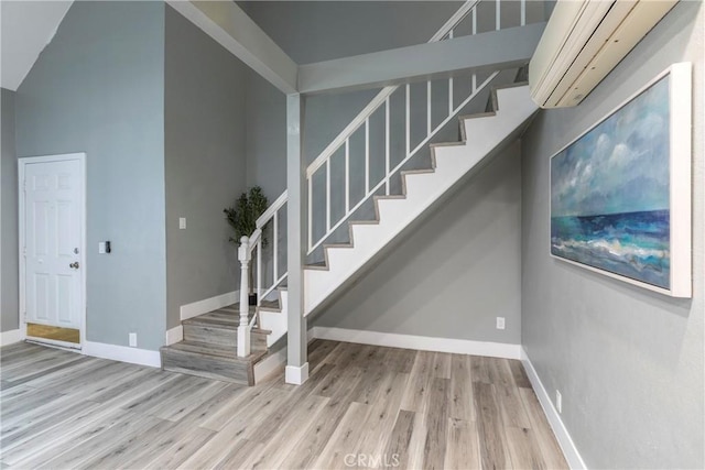 stairs with lofted ceiling, hardwood / wood-style flooring, and a wall mounted AC