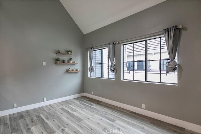 spare room with vaulted ceiling and light hardwood / wood-style flooring