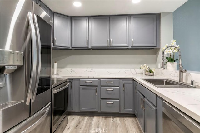 kitchen featuring stainless steel appliances, sink, and gray cabinetry